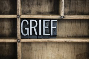 The word "GRIEF" written in vintage metal letterpress type in a wooden drawer with dividers.